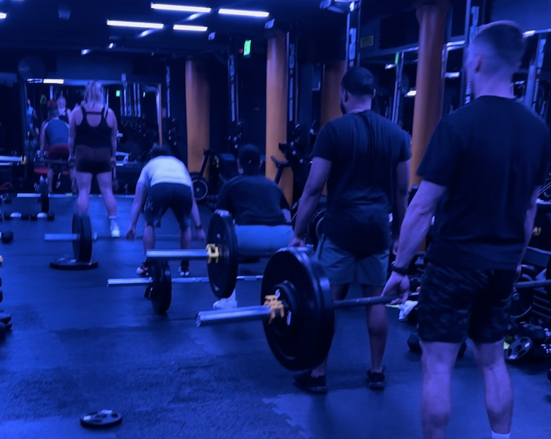 A coach working with members during a barbell class at BronCore Fitness